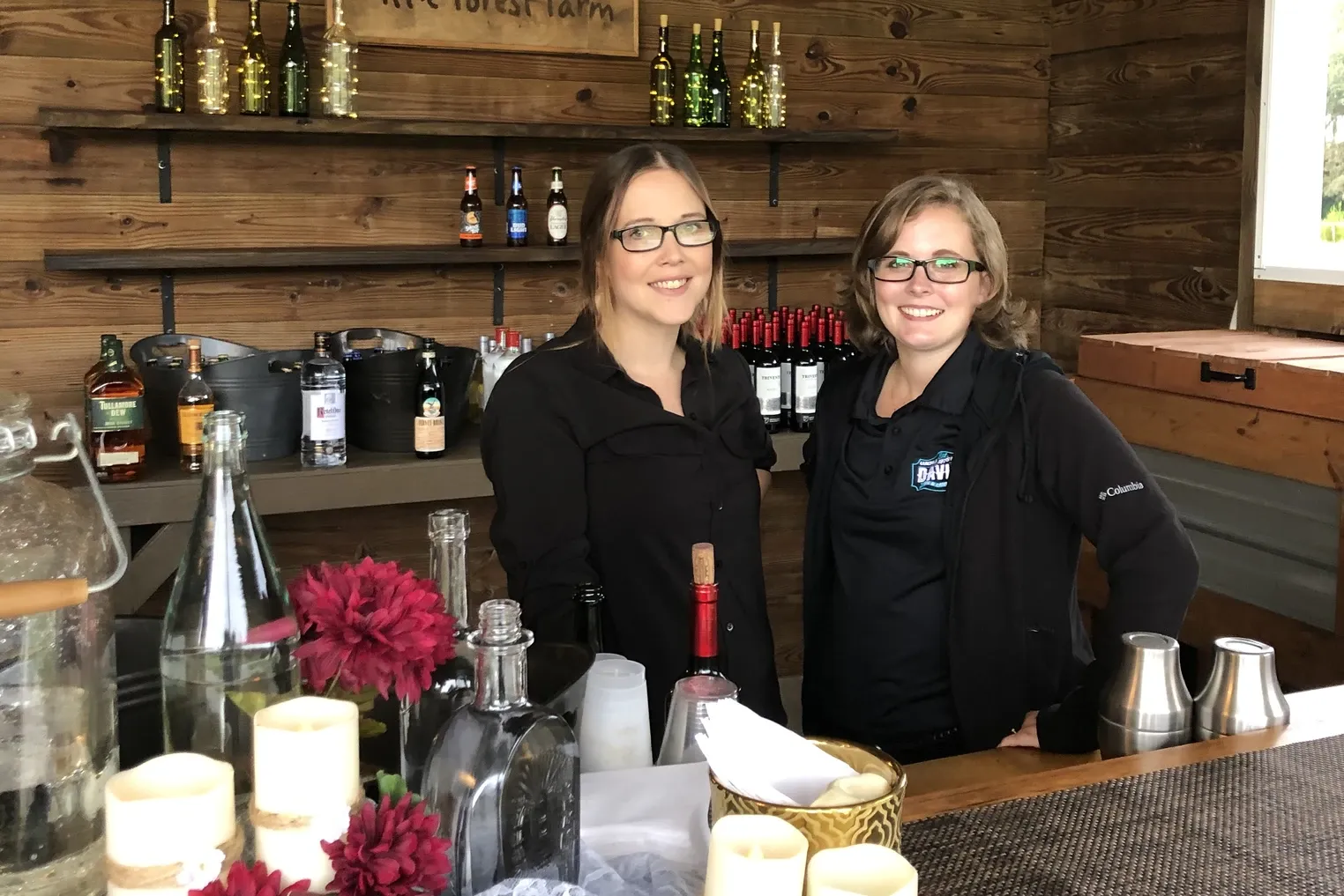 Bartender behind a candlelit bar with flowers and bottles