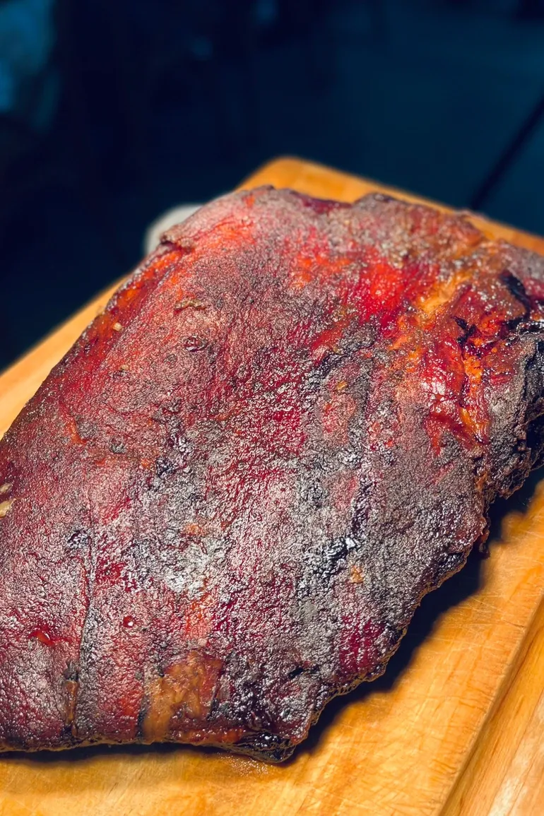Brisket with a deep smoked bark resting on a carving board