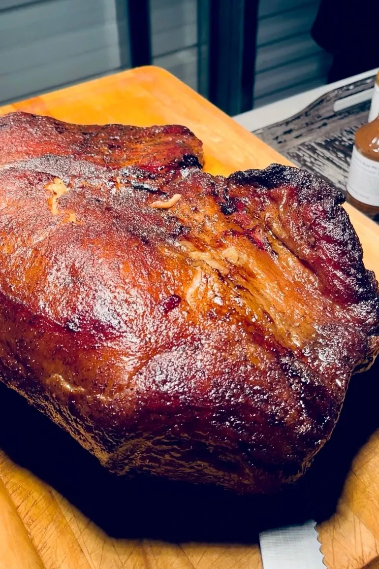 Burnished smoked pork shoulder on a carving board