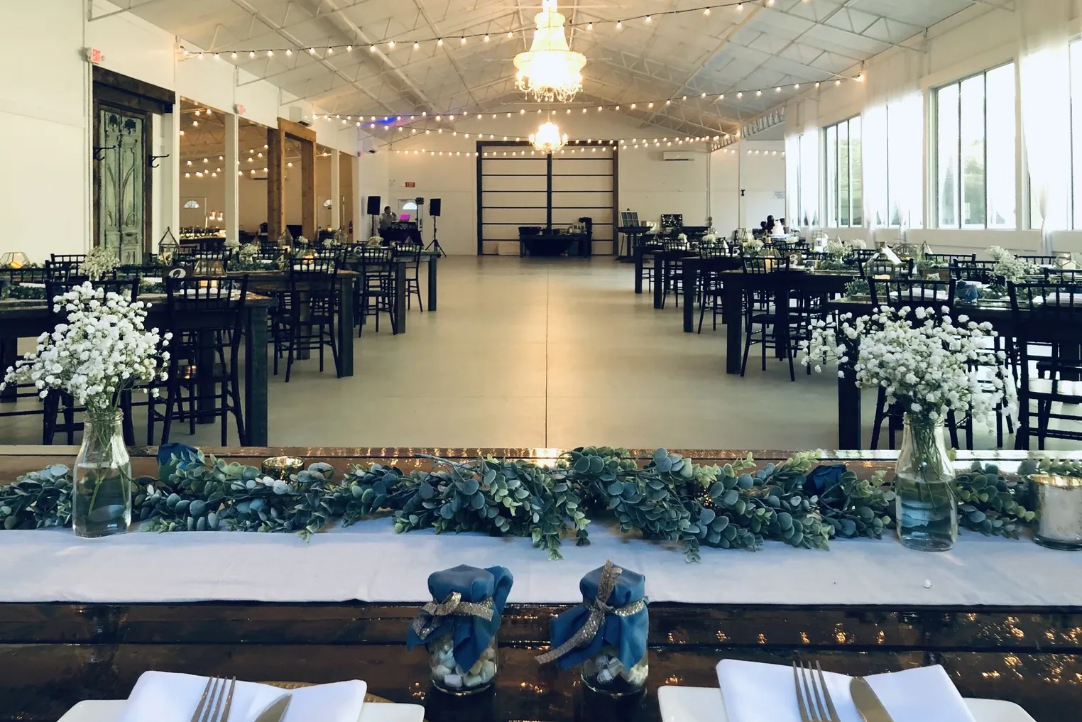 Venue with black tables, baby's breath, and string lights